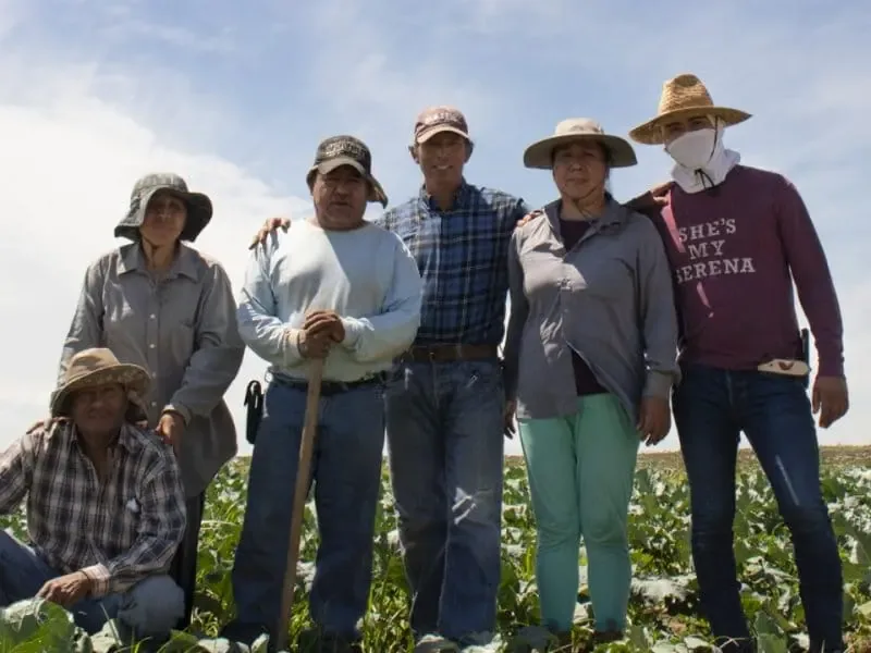 Grupo de produtores rurais reunido em uma plantação, representando uma cooperativa