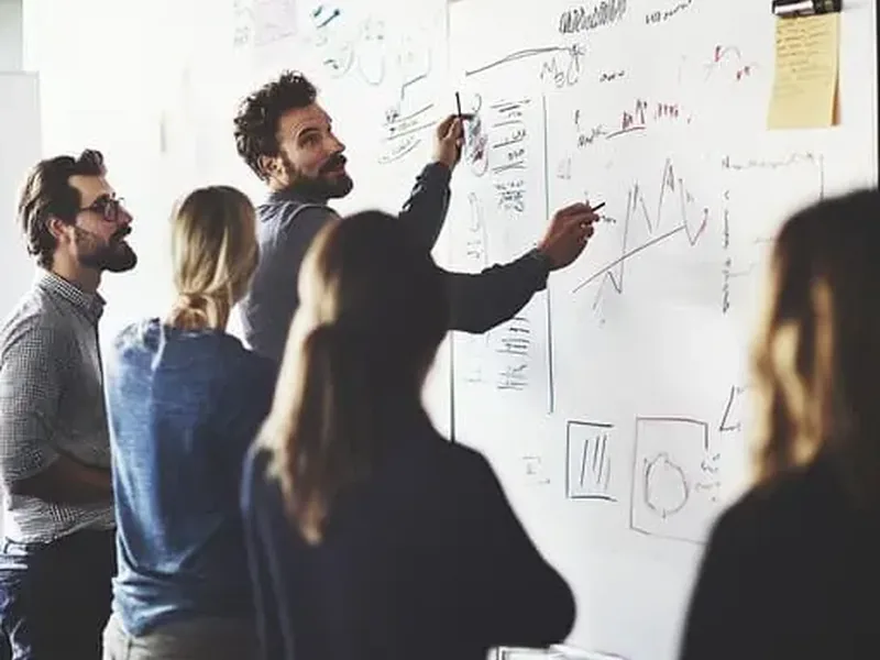 Equipe diante de um quadro branco com esquemas de planejamento estratégico